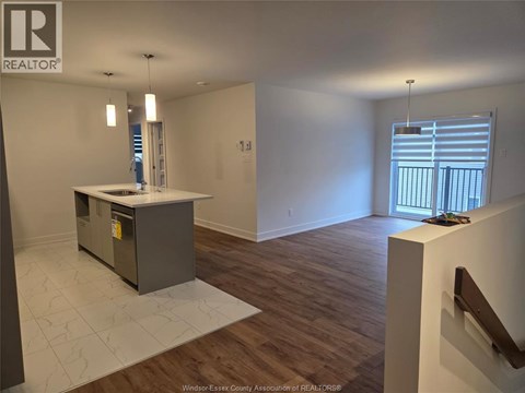 A room with a kitchen island and wooden flooring.