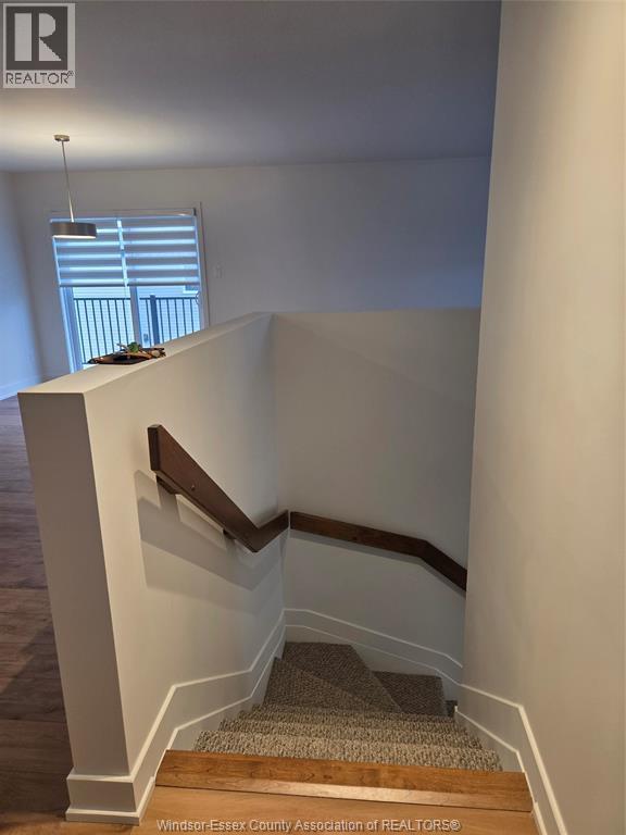 A staircase with a wooden handrail and a carpeted runner.