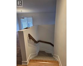 A staircase with a wooden handrail and a carpeted runner.