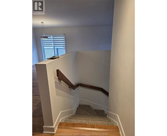 A staircase with a wooden handrail and a carpeted runner.