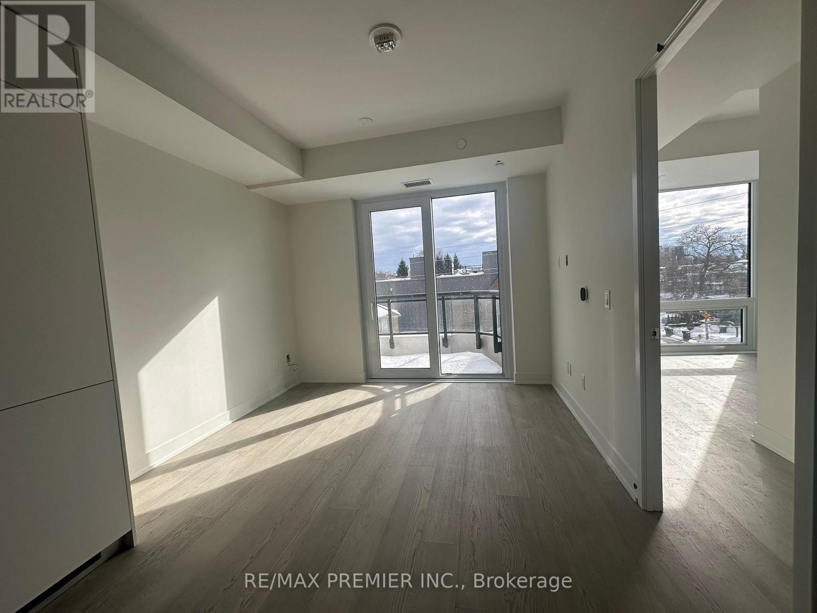 A spacious room with wooden flooring and a large window overlooking a snowy landscape.