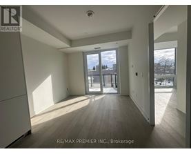 A spacious room with wooden flooring and a large window overlooking a snowy landscape.