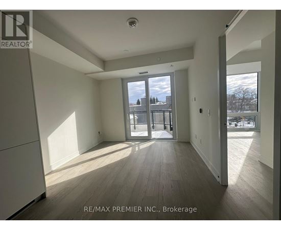 A spacious room with wooden flooring and a large window overlooking a snowy landscape.