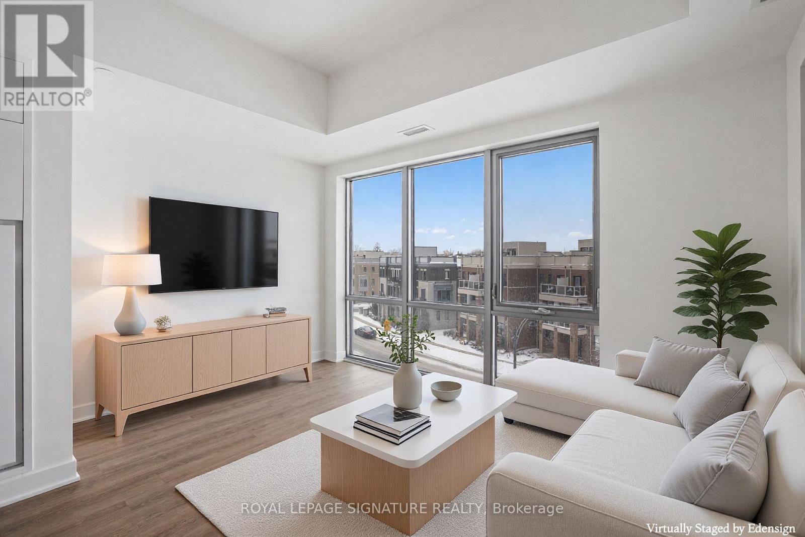 A living room with a large window, a white couch, and a wooden coffee table.