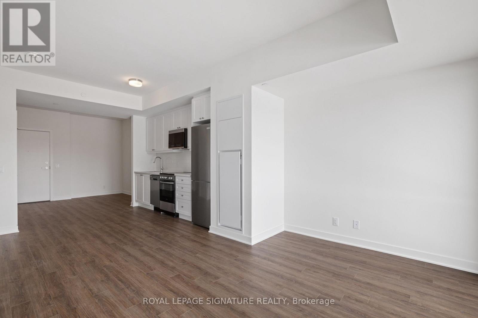 A spacious, empty room with wood flooring and white walls.