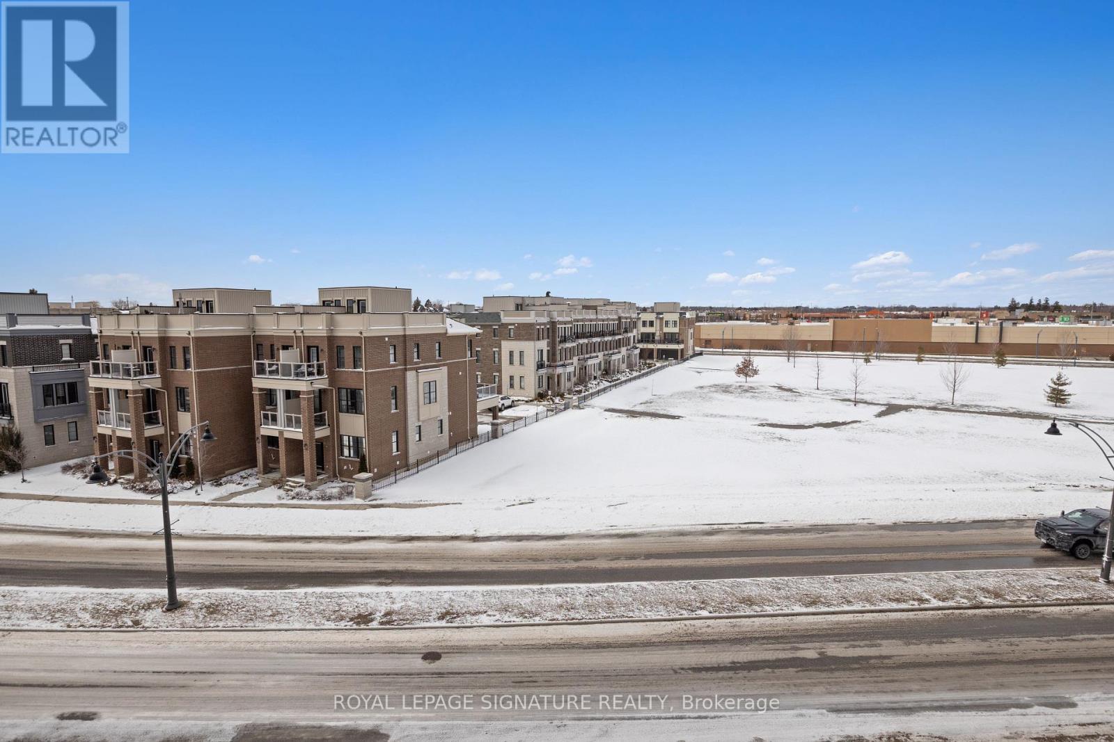 A snowy landscape with apartment buildings and a car on the road.
