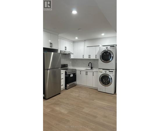 A modern kitchen with wooden floors and stainless steel appliances.