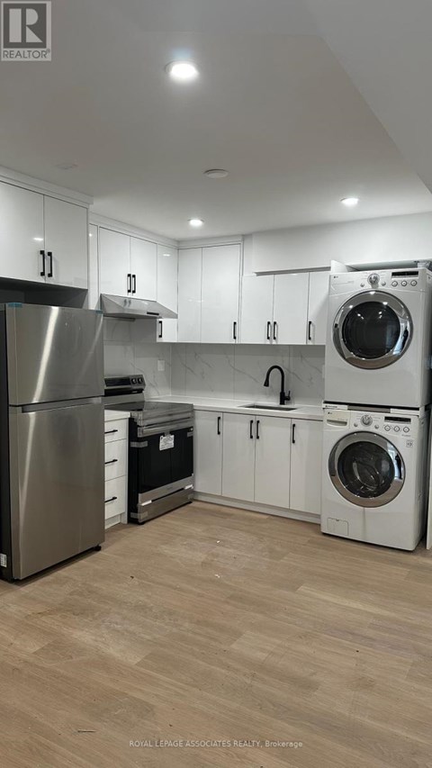 A modern kitchen with wooden floors and stainless steel appliances.