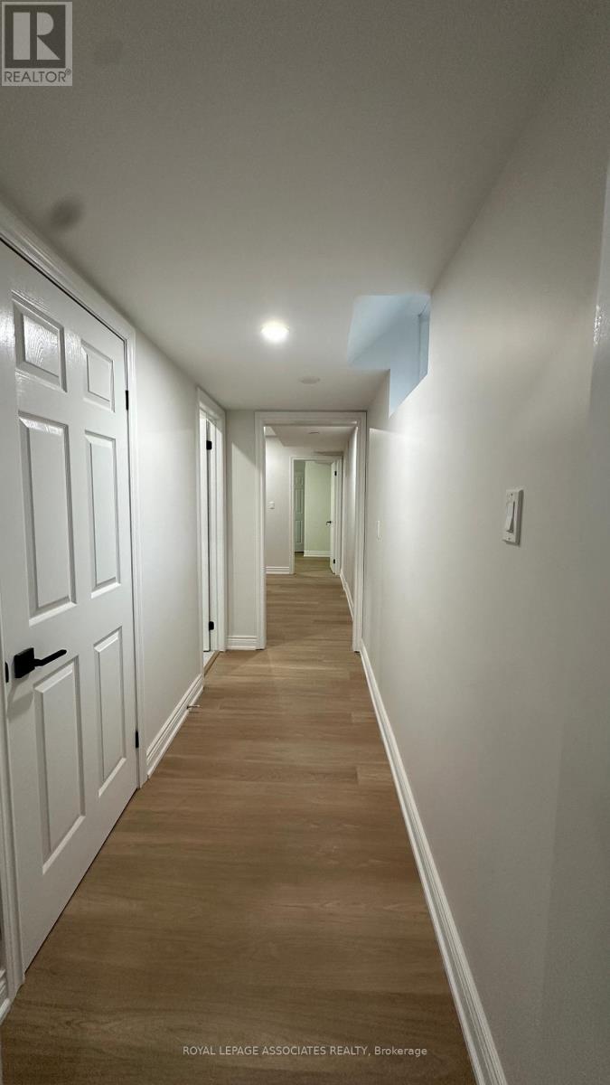 A long hallway with white doors and wooden floors.