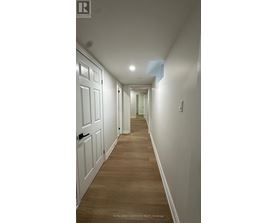 A long hallway with white doors and wooden floors.