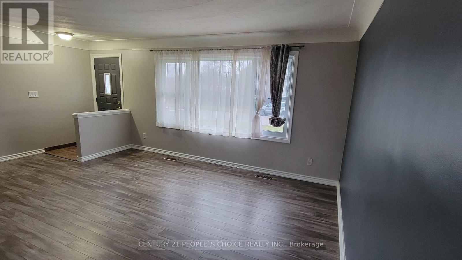 A room with wooden flooring and a window with curtains.