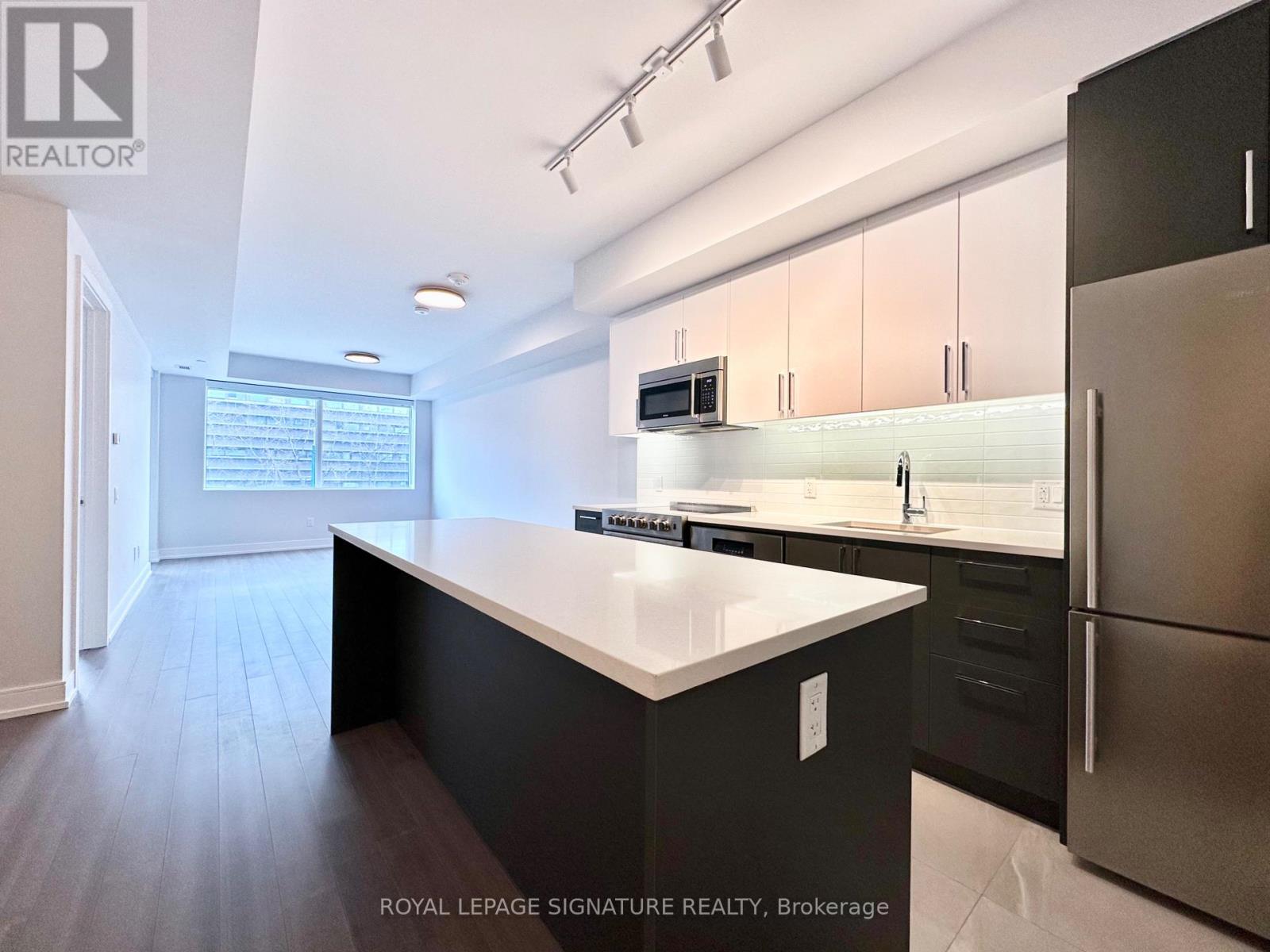 A modern kitchen with a large island and stainless steel appliances.