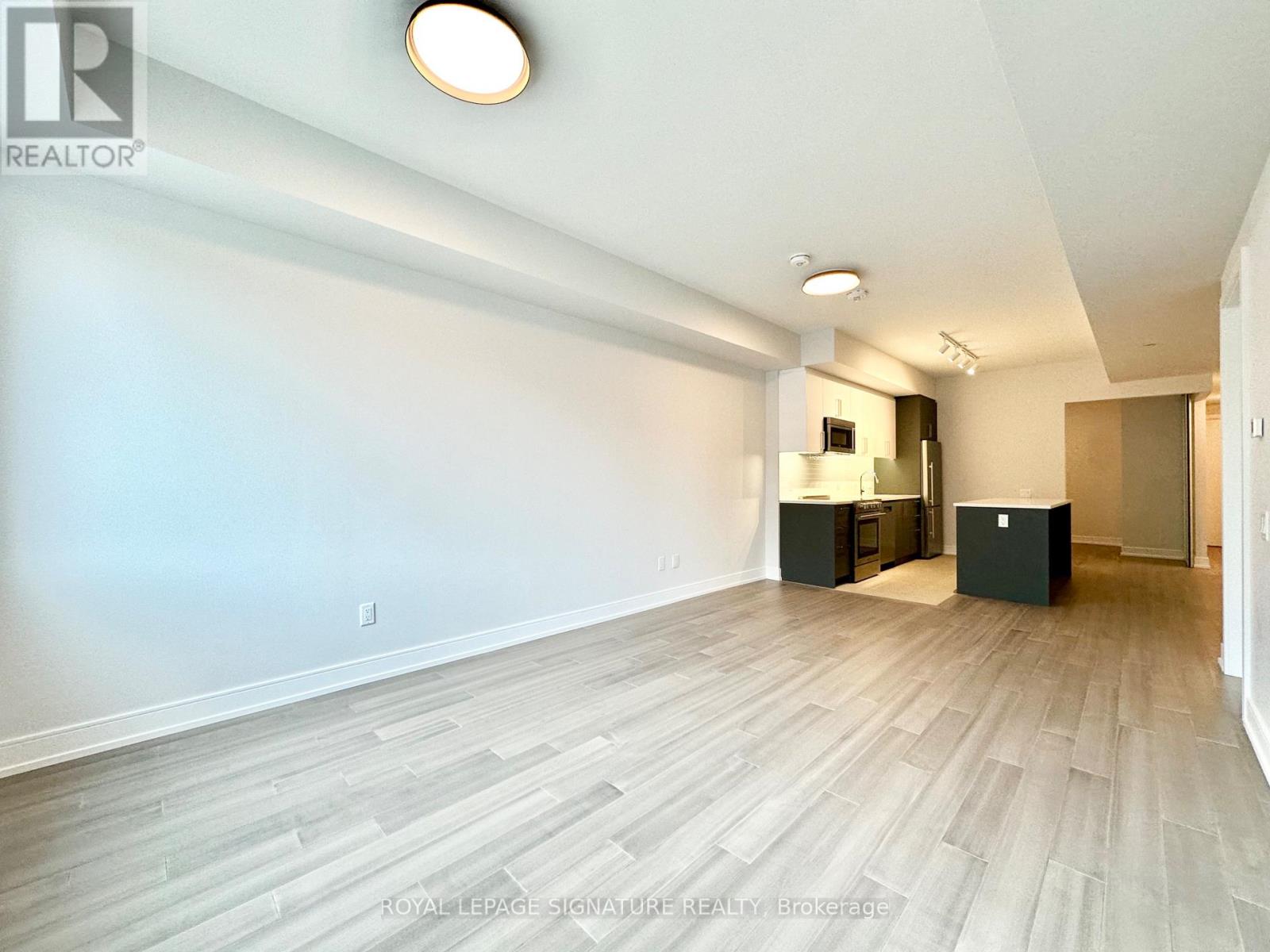 A spacious room with light wood flooring and white walls.