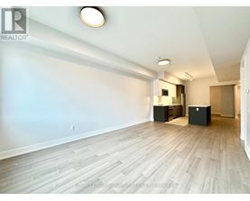 A spacious room with light wood flooring and white walls.