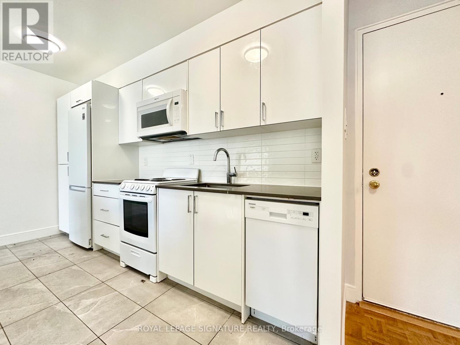 A white kitchen with a refrigerator, microwave, oven, and dishwasher.