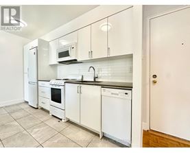 A white kitchen with a refrigerator, microwave, oven, and dishwasher.