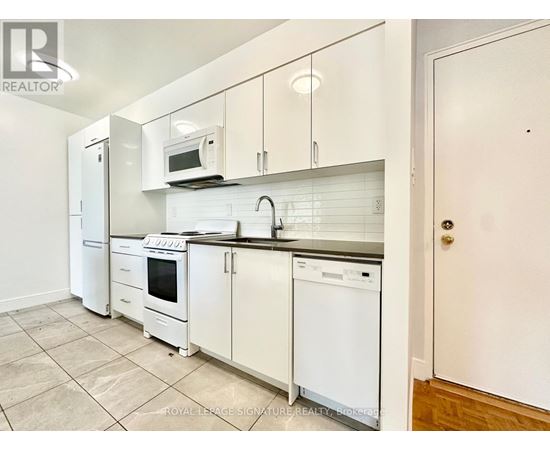 A white kitchen with a refrigerator, microwave, oven, and dishwasher.