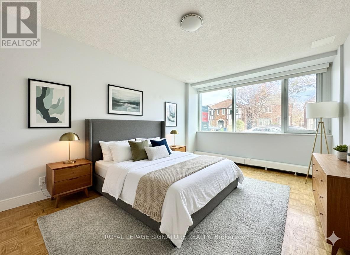 A bedroom with a large bed, a nightstand, and a window.