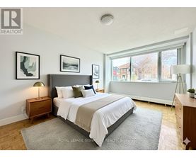 A bedroom with a large bed, a nightstand, and a window.