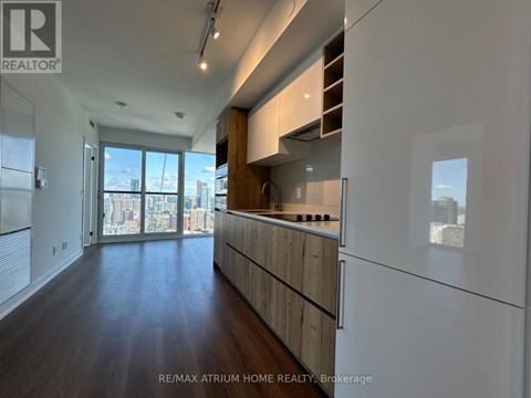 A spacious kitchen with wooden cabinets and a view of the city through the window.