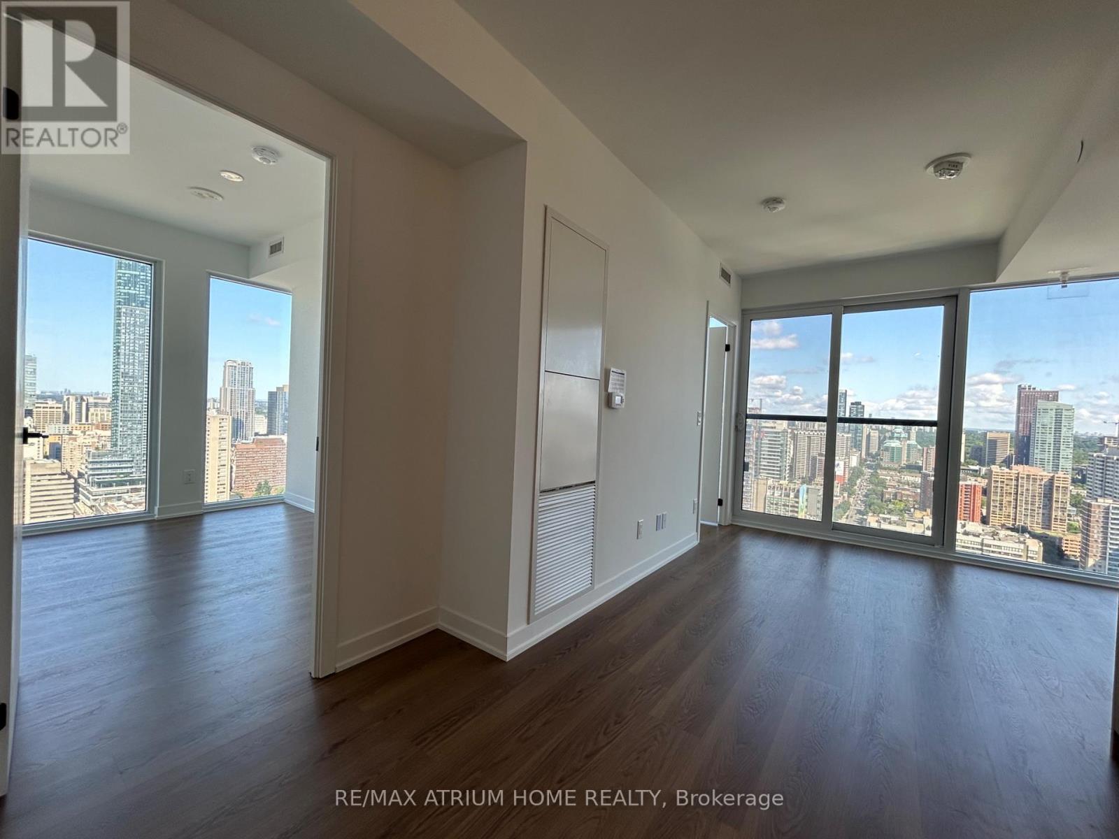 A spacious room with wooden floors and large windows overlooking a cityscape.