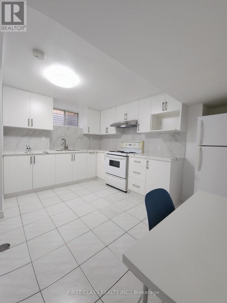 A white kitchen with a marble counter top and a single blue chair.