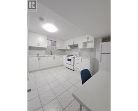 A white kitchen with a marble counter top and a single blue chair.
