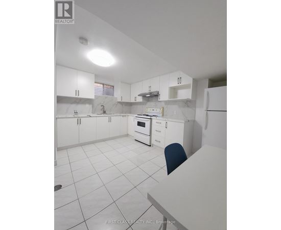 A white kitchen with a marble counter top and a single blue chair.