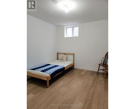 A bedroom with a bed, a chair, and a window.