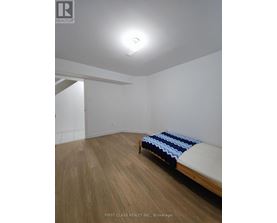 A bedroom with a bed and wooden floors.