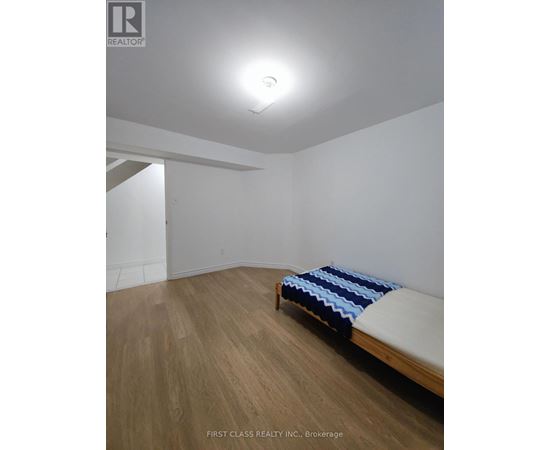 A bedroom with a bed and wooden floors.