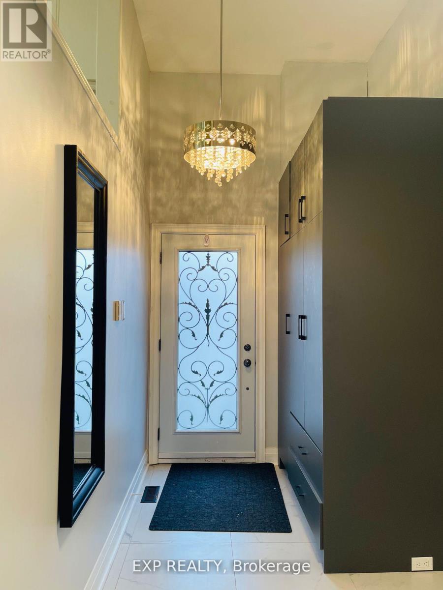 A hallway with a chandelier, a door with a glass window and a black door.
