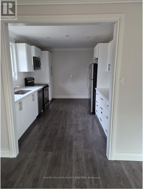 A kitchen with white cabinets and a black fridge.