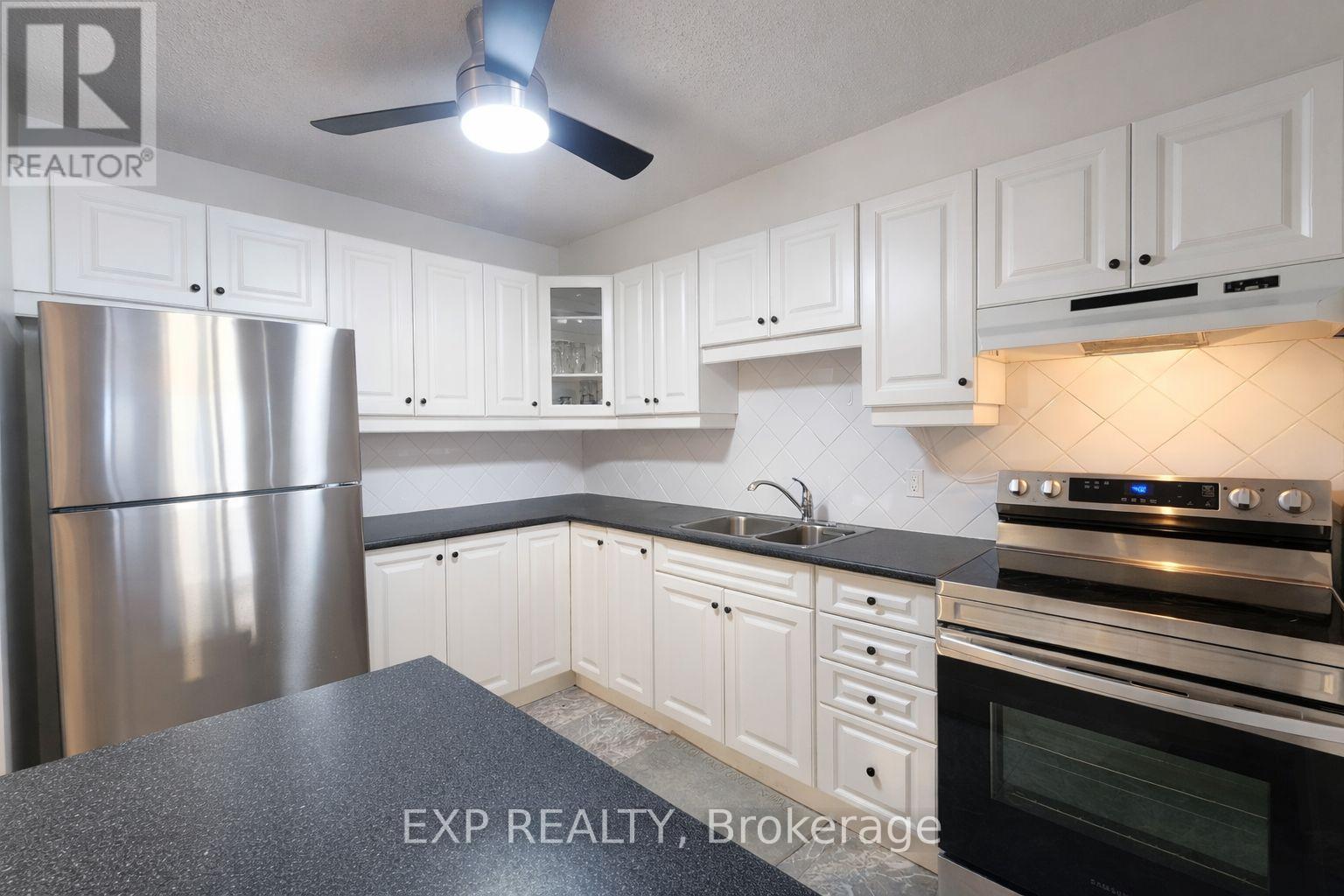 A kitchen with white cabinets and a stainless steel refrigerator.