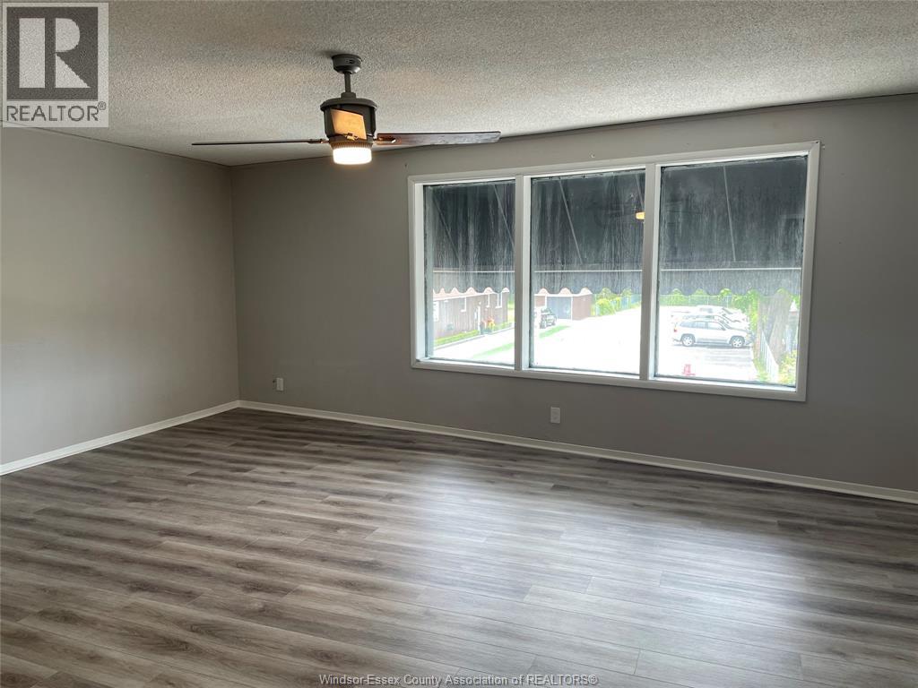 A room with a large window and wooden flooring.