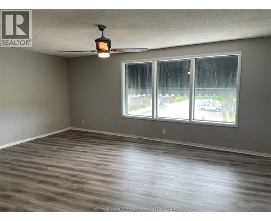 A room with a large window and wooden flooring.