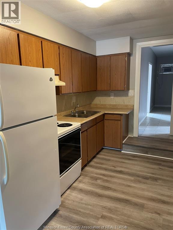 A kitchen with a white refrigerator and wooden cabinets.