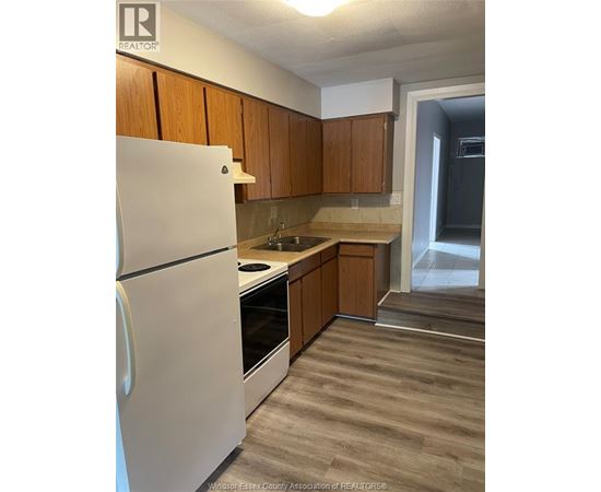 A kitchen with a white refrigerator and wooden cabinets.