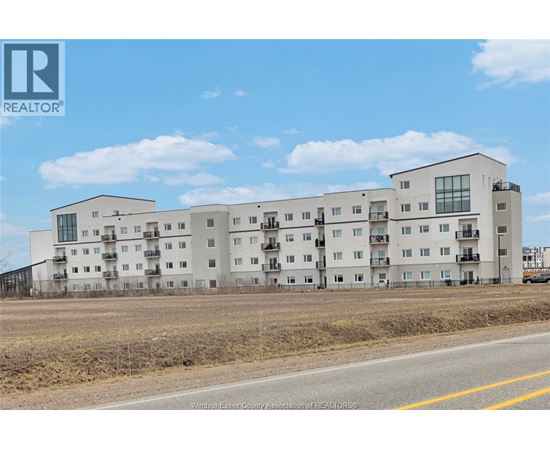 A large white apartment building with a REALTOR® logo in the corner.