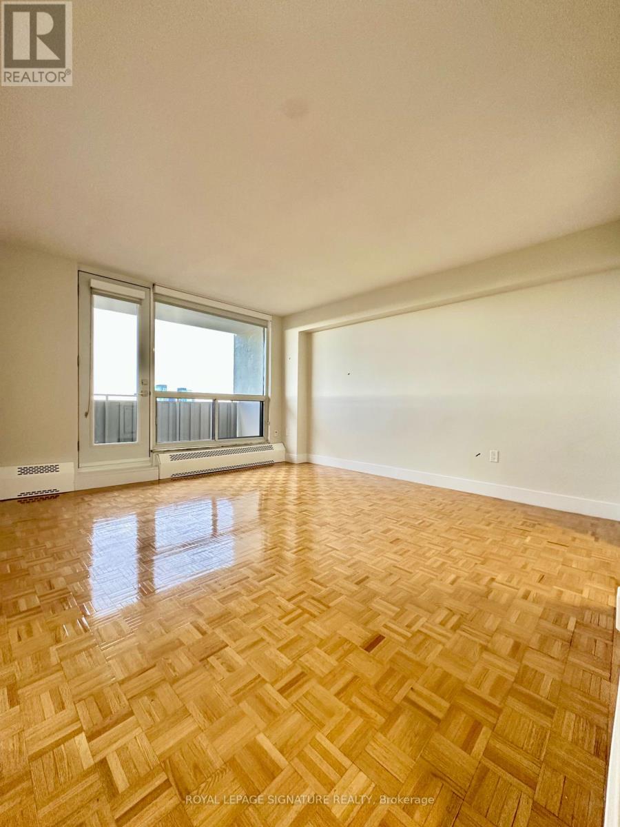 A room with wooden flooring and a window overlooking a balcony.