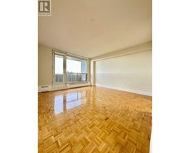 A room with wooden flooring and a window overlooking a balcony.