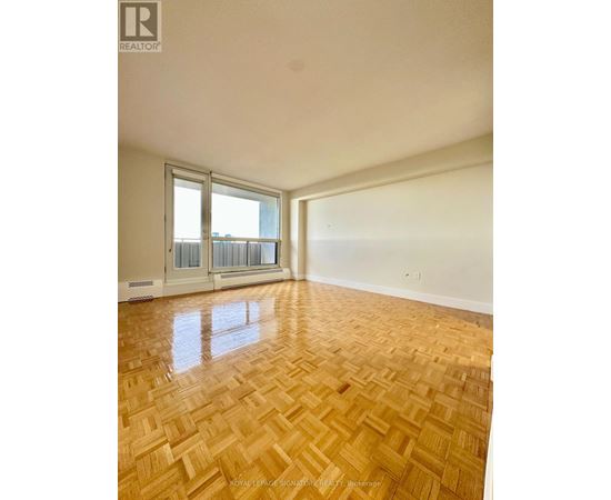 A room with wooden flooring and a window overlooking a balcony.