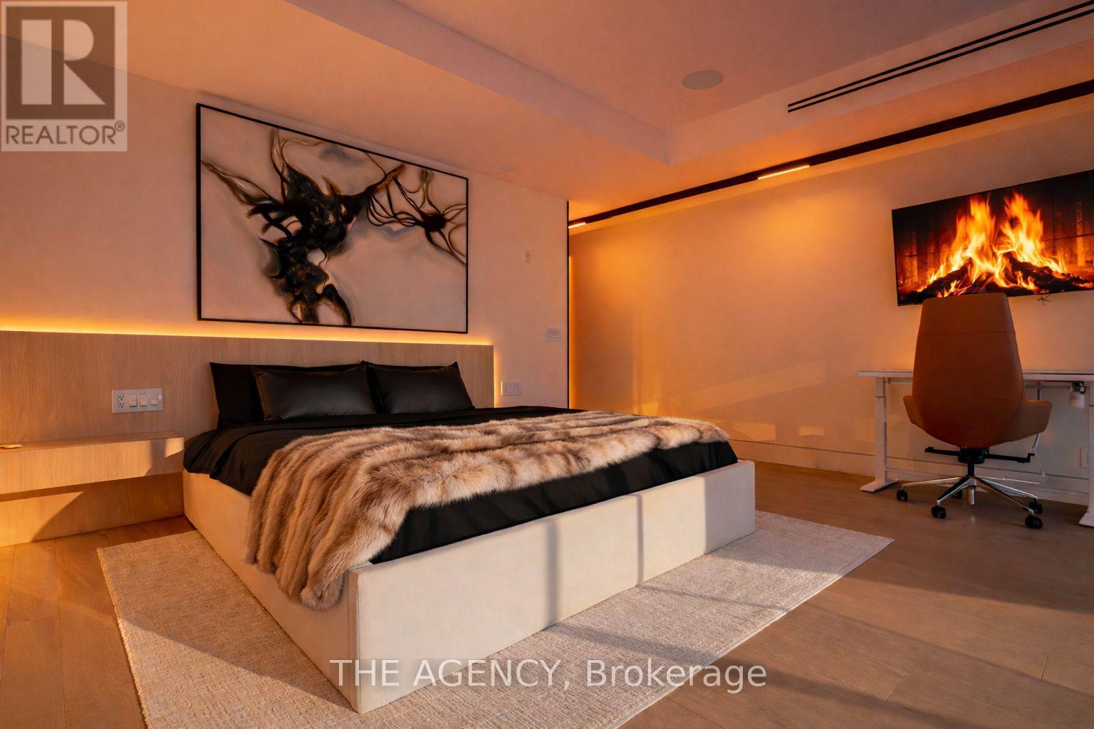 A modern bedroom with a large bed and a fireplace.