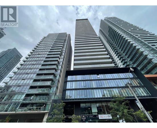 A tall building with a glass facade stands in front of other skyscrapers.