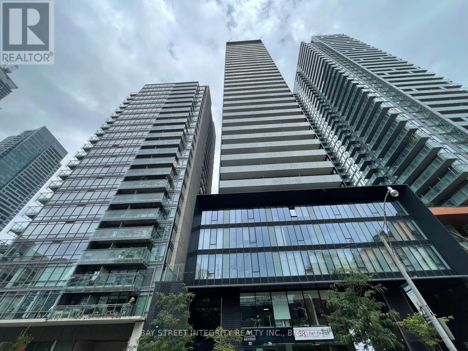 A tall building with a glass facade stands in front of other skyscrapers.