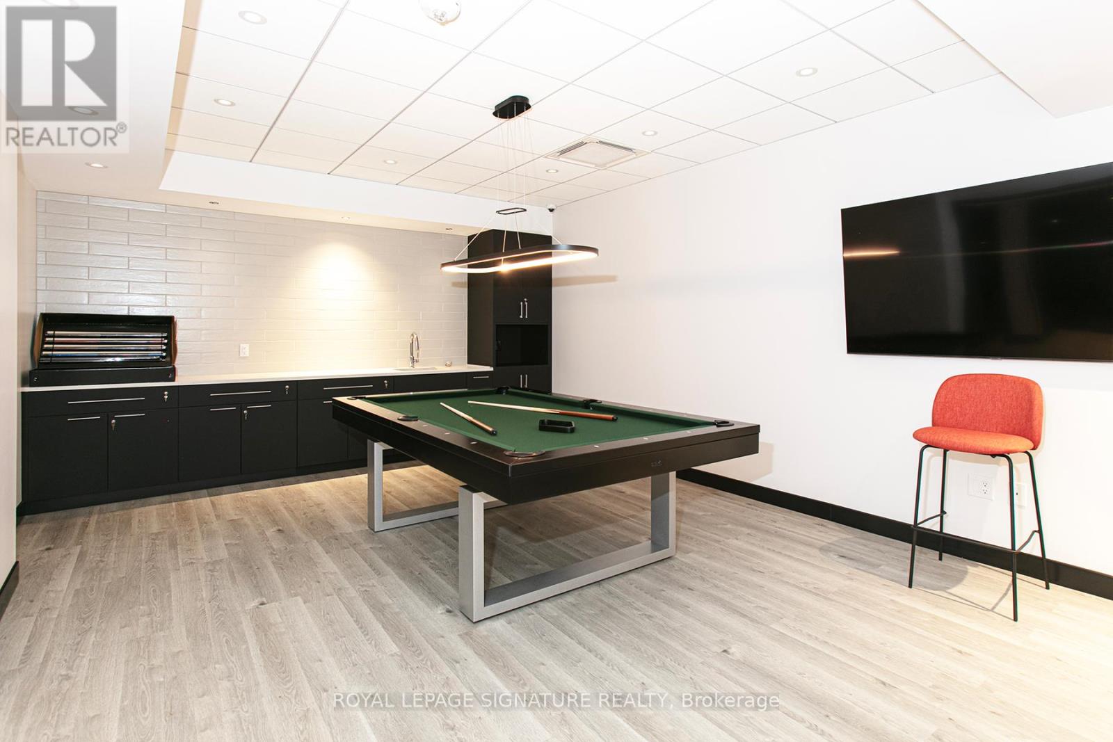 A pool table in a room with a chair and a television.