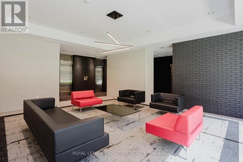 A living room with a black couch and a red chair.