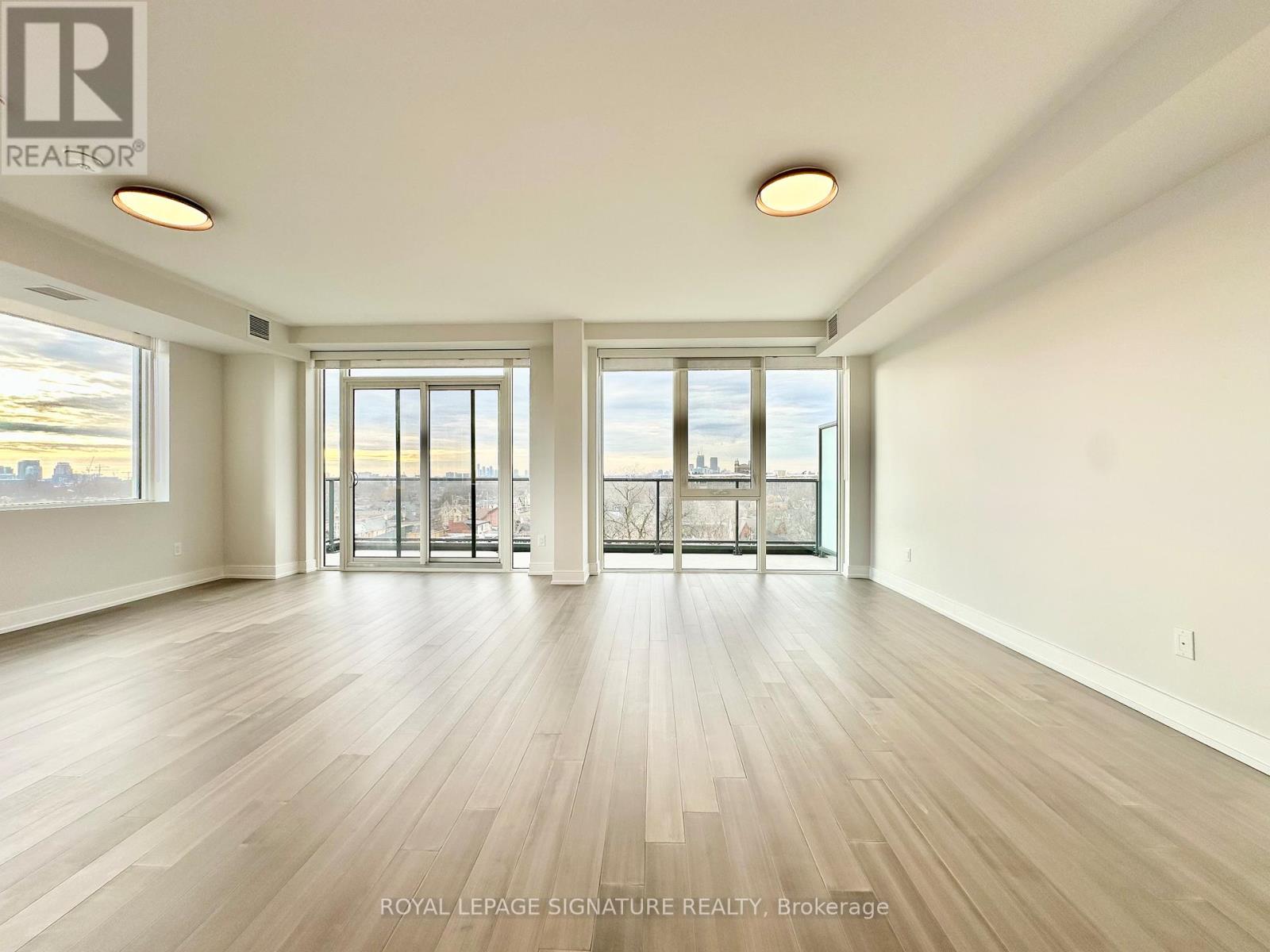 A spacious room with wooden flooring and large windows.