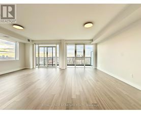 A spacious room with wooden flooring and large windows.