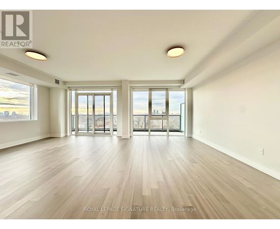 A spacious room with wooden flooring and large windows.